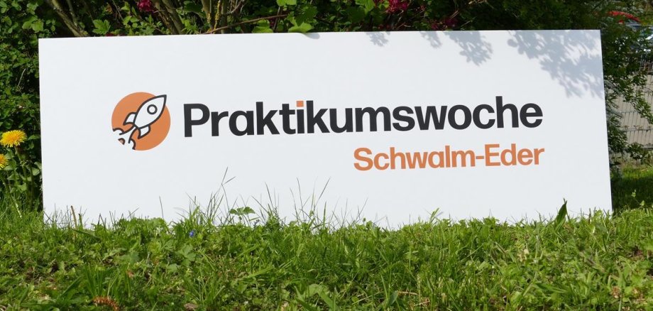 Plakat mit Aufschrift Praktikumswoche Schwalm-Eder auf grüner Wiese. 