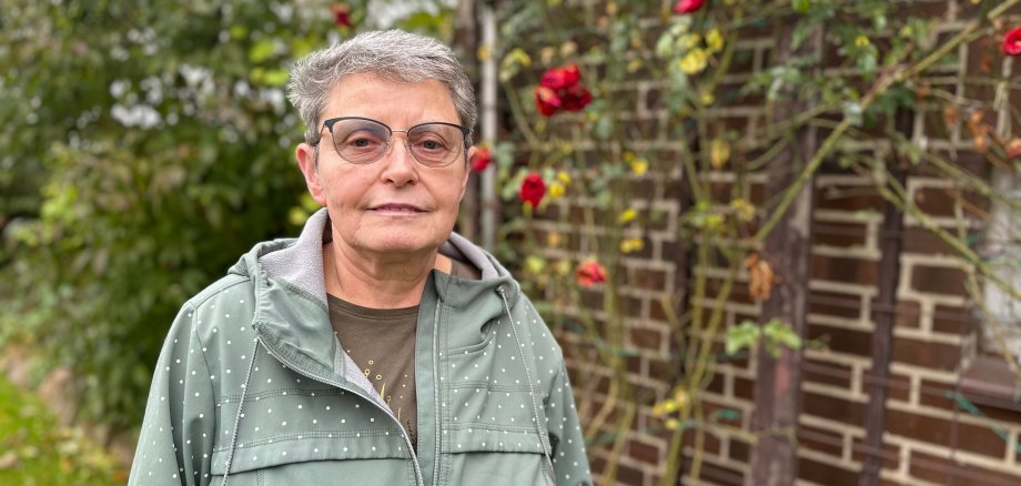 Frau im Garten vor Rosenstock